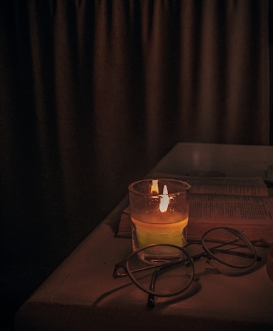 A cozy evening scene with headphones resting on a stack of books beside a gently flickering candle