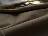 Close-up of a beige textured fabric with subtle gold accents under soft lighting.