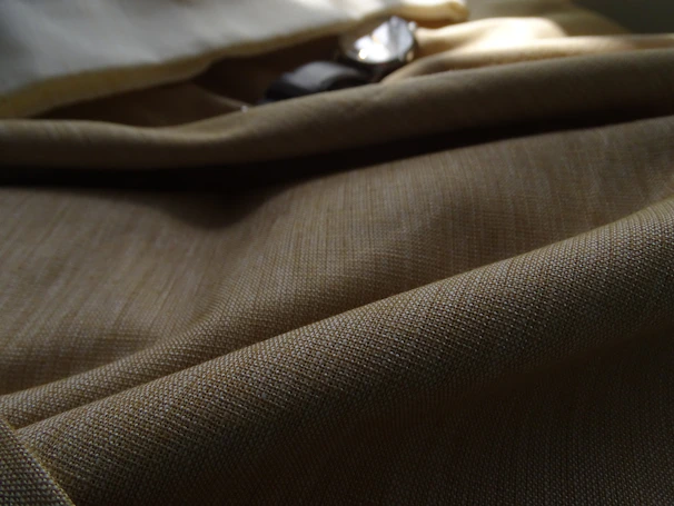 Close-up of a soft, luxurious fabric texture in a warm beige tone, highlighting the quality craftsmanship of Jamali Aura apparel.