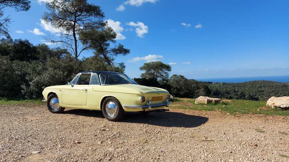yellow coupe on brown dirt ground during daytime