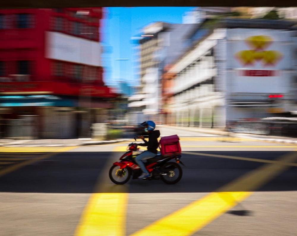 Hombre en chaqueta roja montando motocicleta en la carretera durante el día