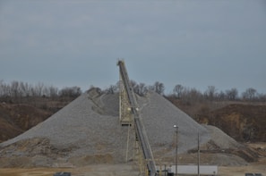Processing plant with conveyor belts moving stone and gravel under bright industrial lights
