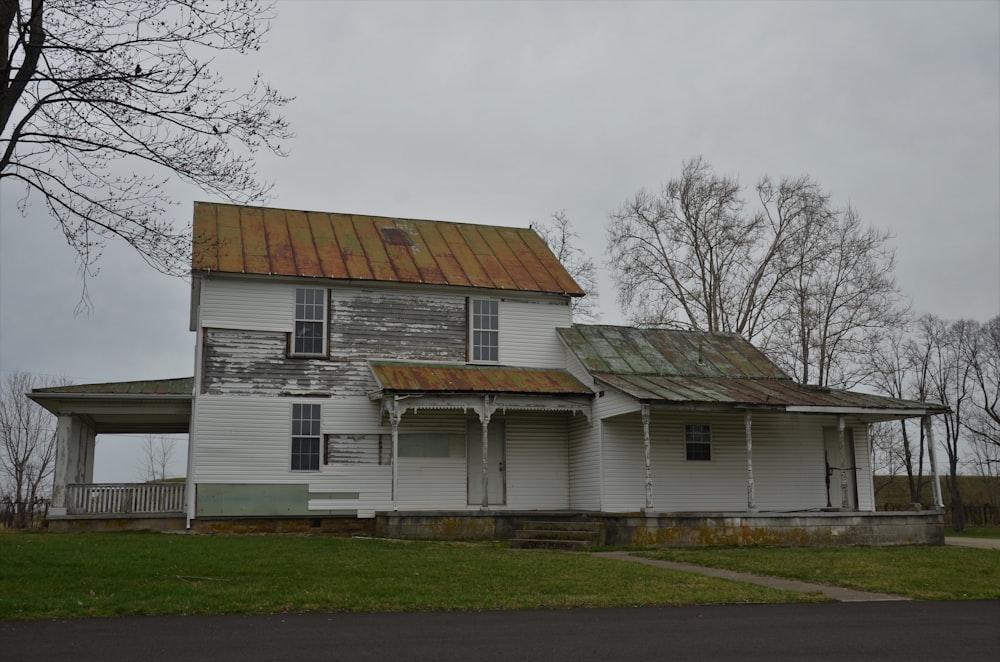 white and brown wooden house near bare trees under white sky during daytime