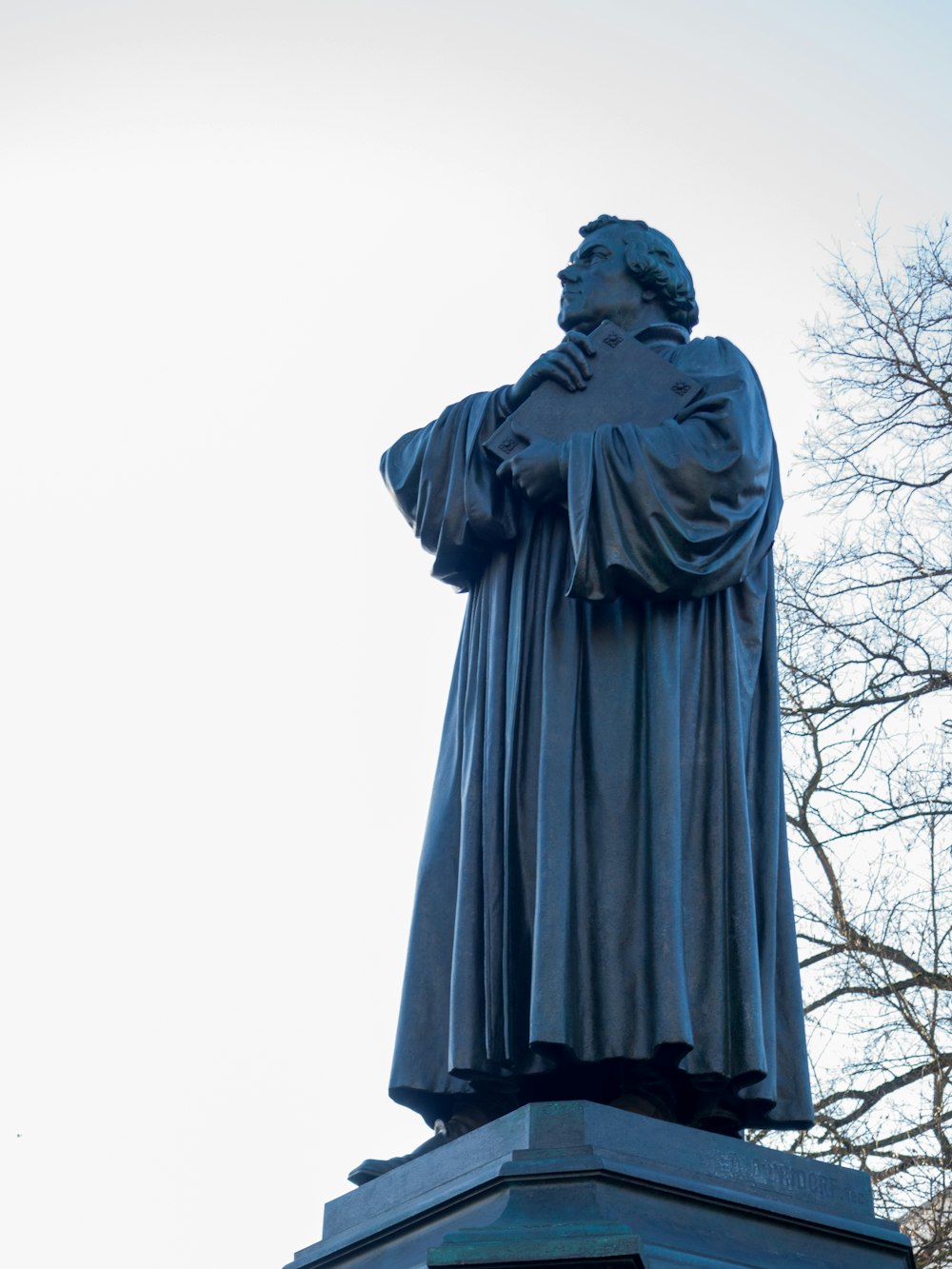 man statue near bare trees during daytime