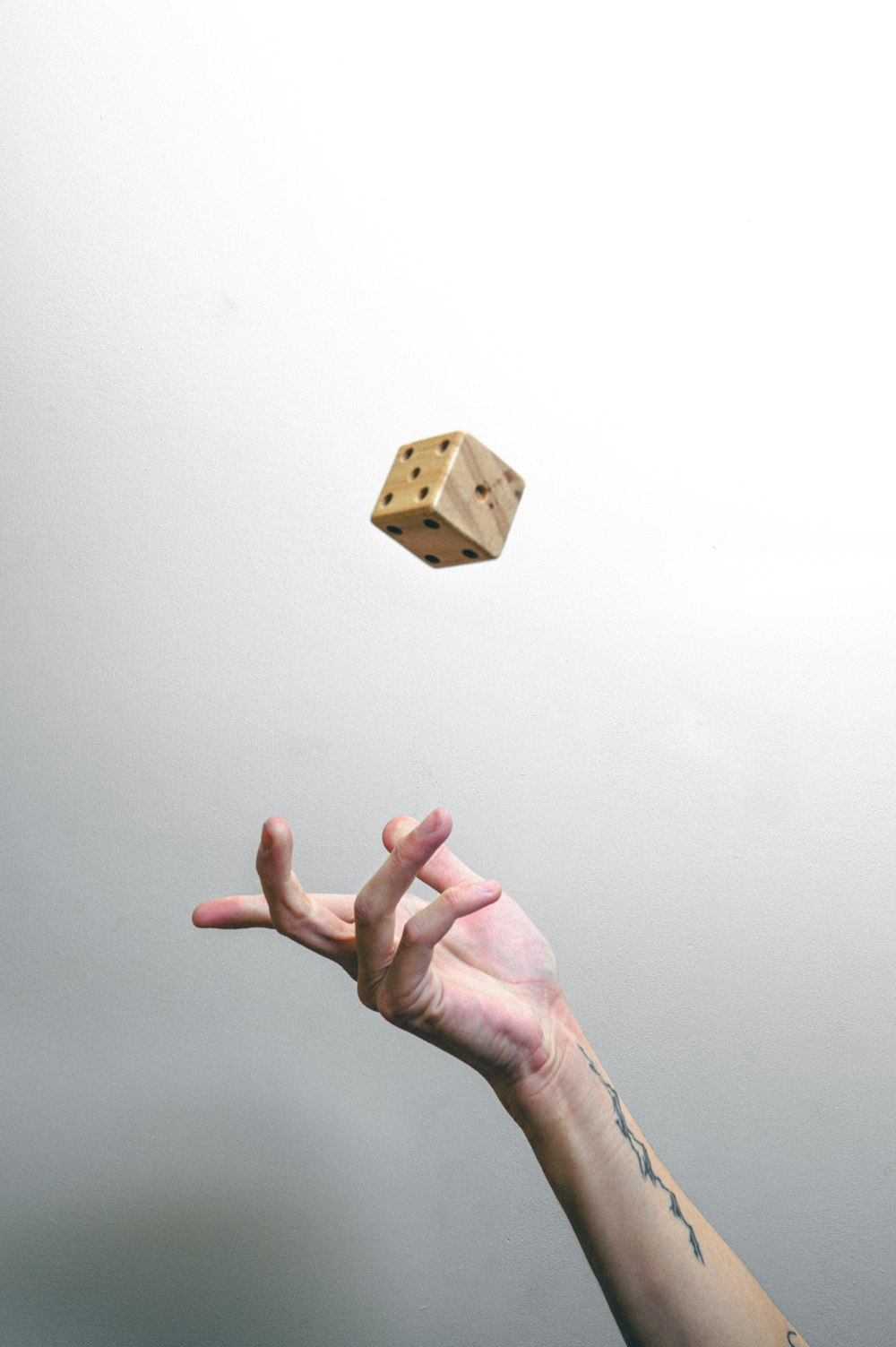 person holding brown wooden cube