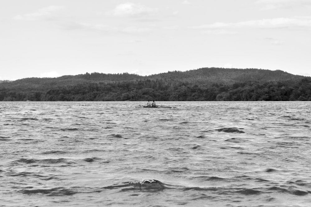 바다에서 보트를 타고 있는 2명의 회색조 사진