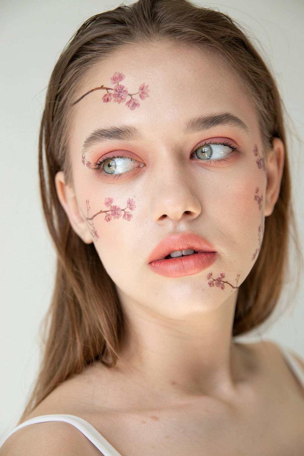 Femme avec de la peinture florale rose et blanche pour le visage