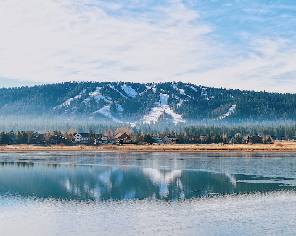 snow covered mountain near lake under cloudy sky during daytime