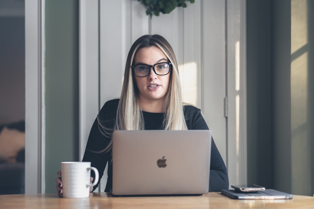Frau in schwarz gerahmter Brille mit MacBook