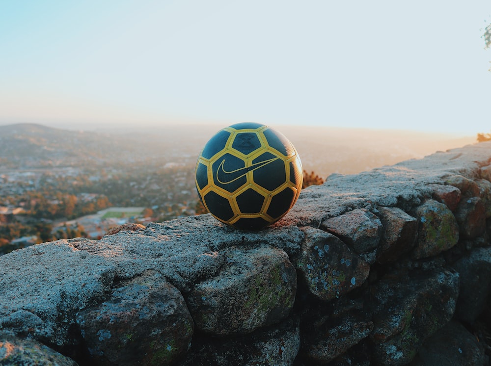 black and white soccer ball on black rock