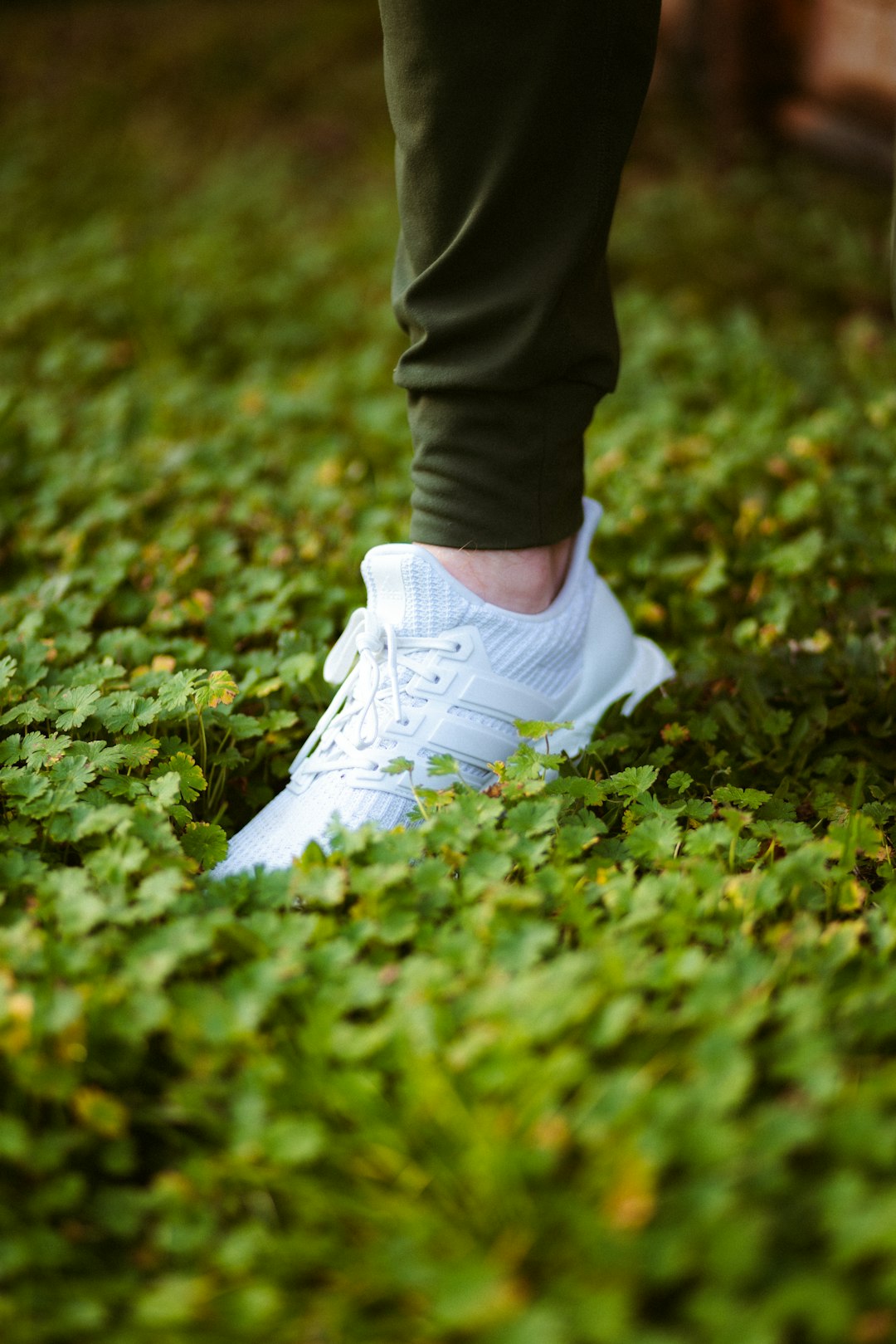 person in black pants and white nike sneakers standing on green grass field during daytime