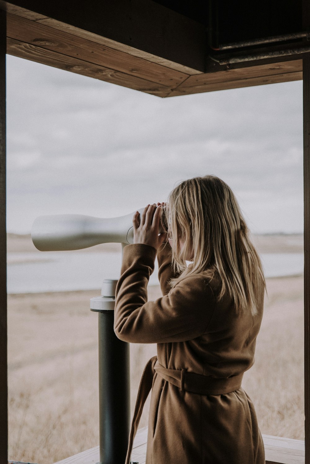 woman in brown long sleeve shirt leaning on white metal post during daytime