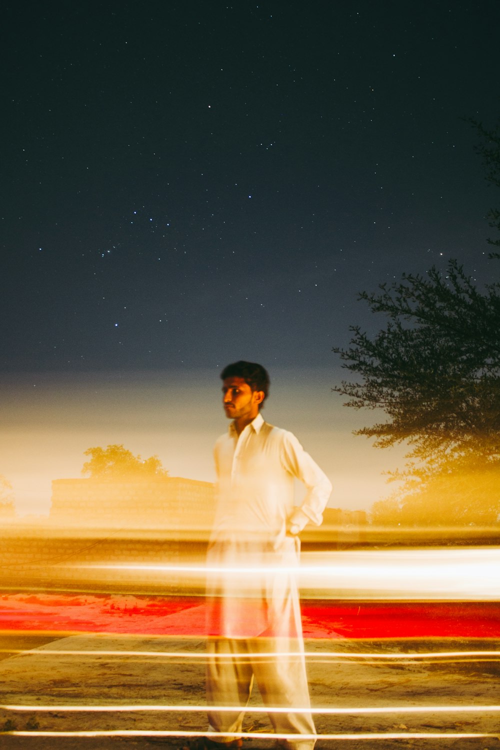 man in white dress shirt standing near body of water during night time