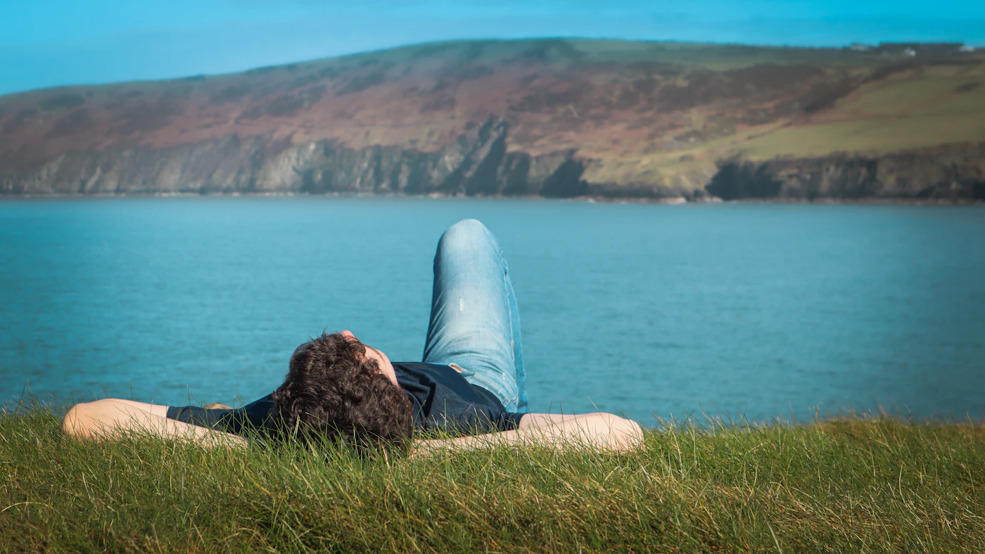 Una persona descansa en el pasto frente al mar