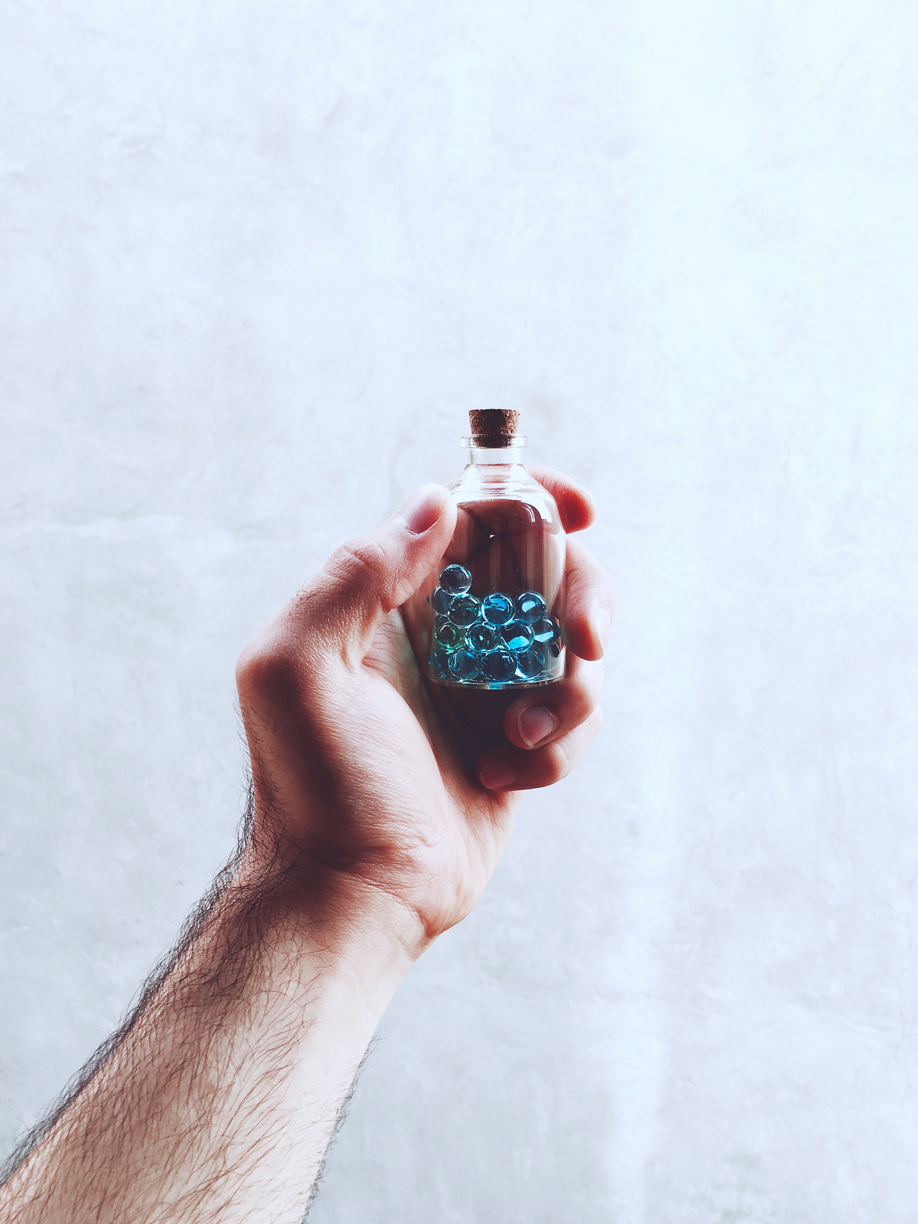 person holding blue and white glass bottle