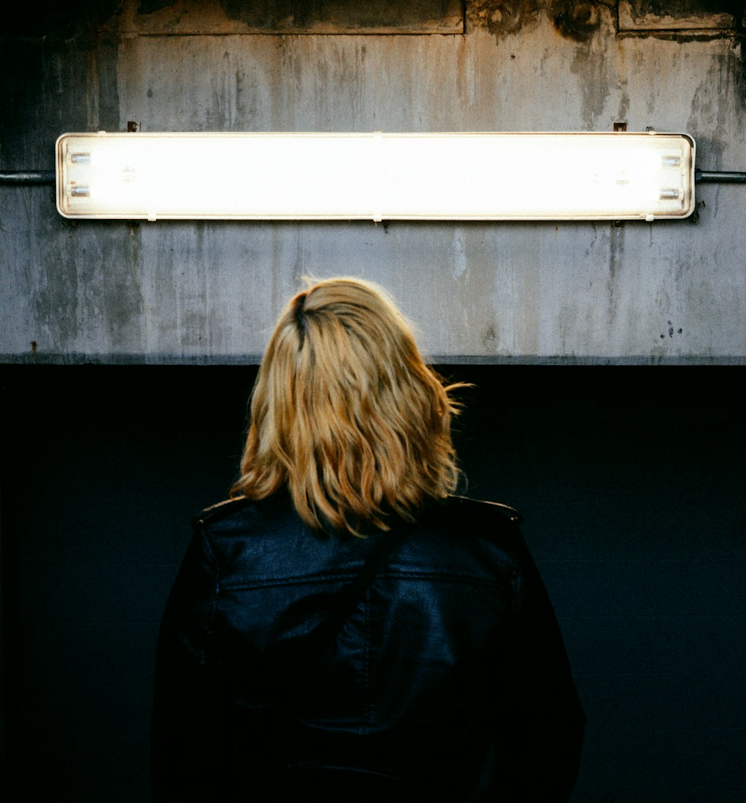 woman in black jacket standing near white wall
