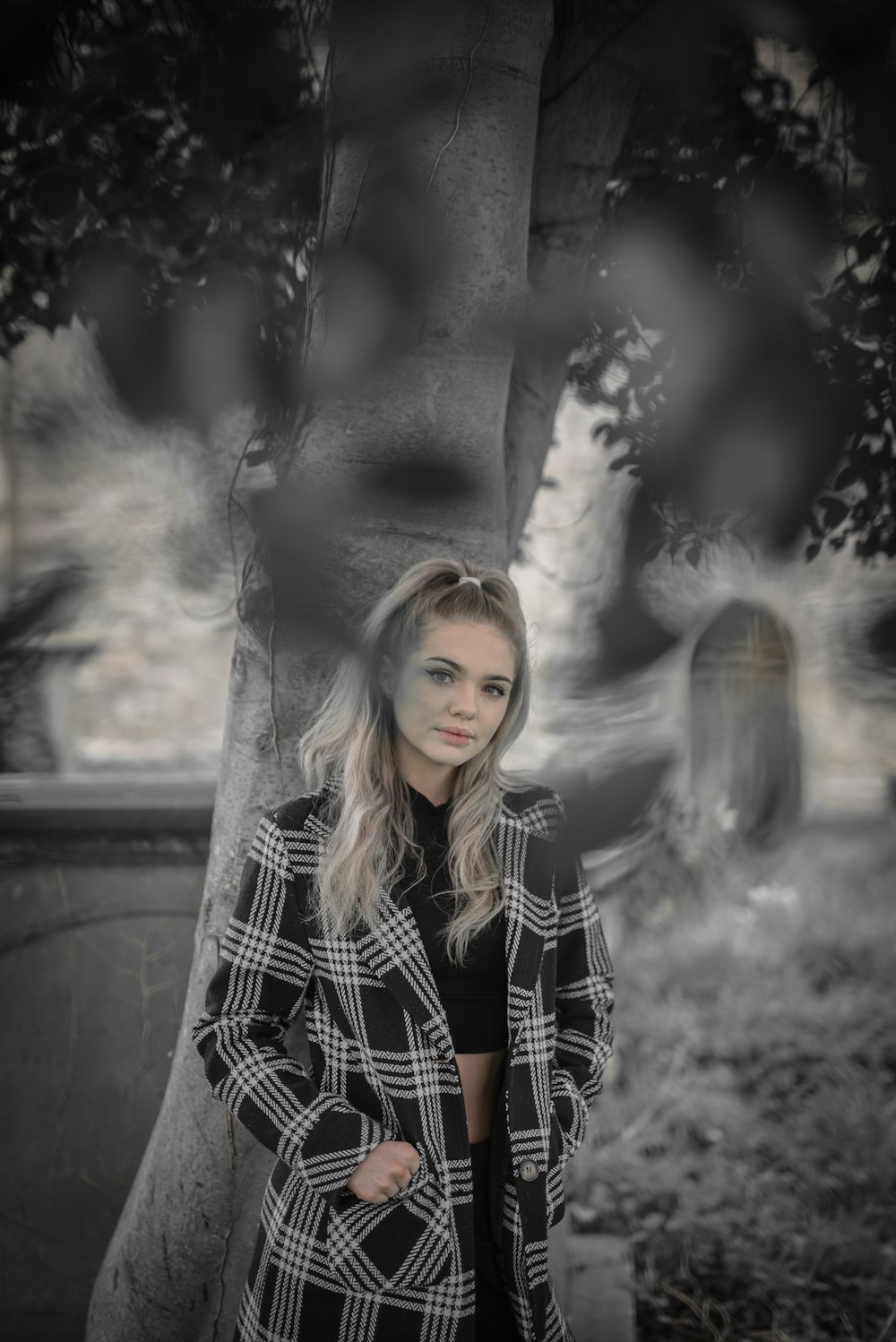 woman in black and white checkered coat standing on gray concrete wall