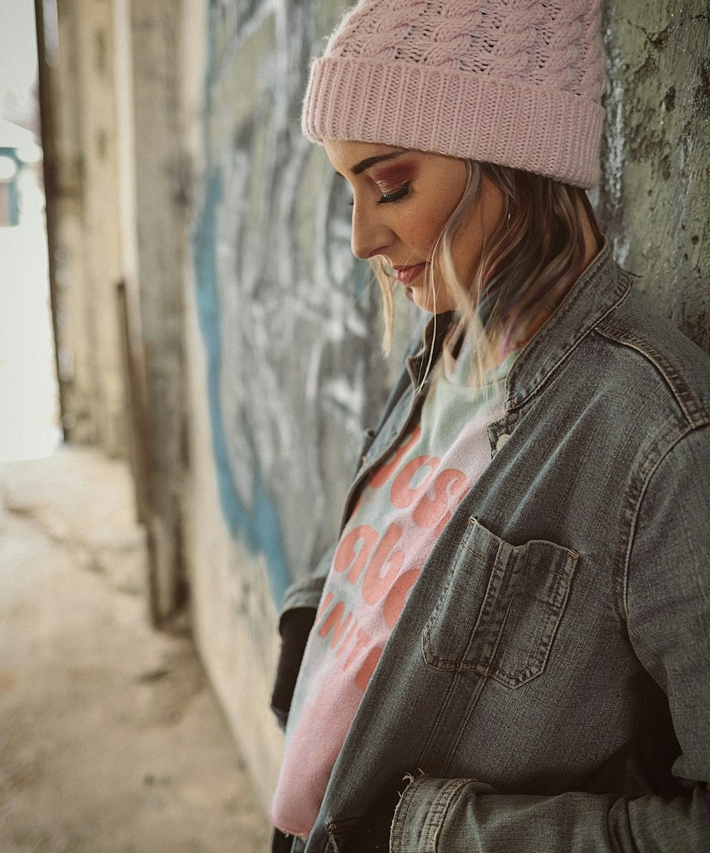 woman in gray denim jacket wearing pink knit cap