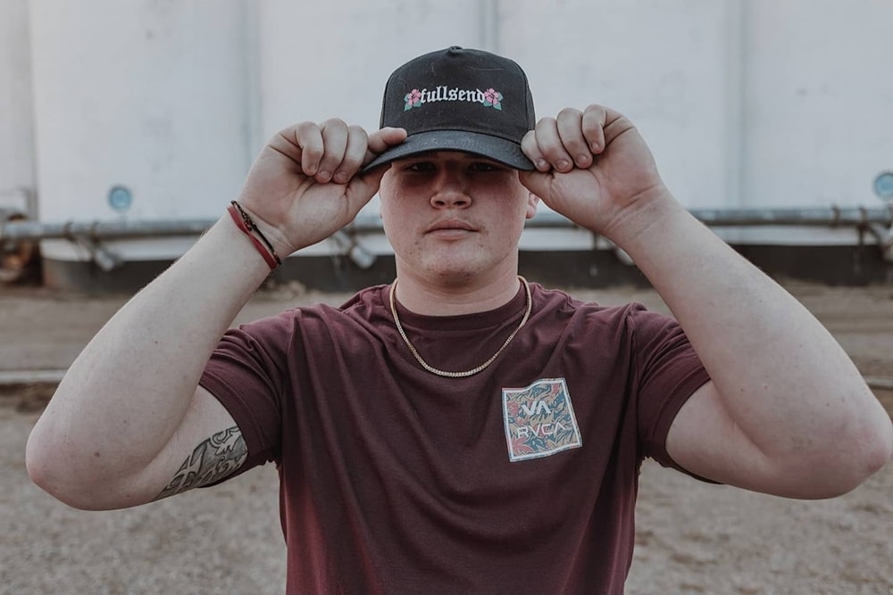 man in brown crew neck t-shirt wearing black cap