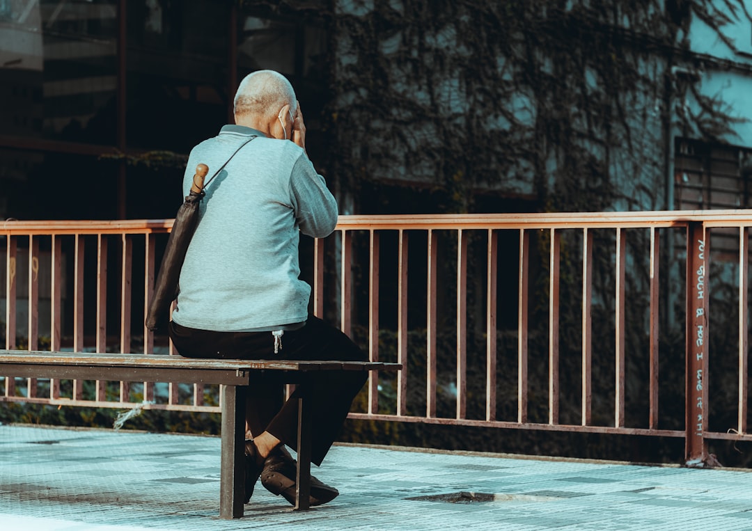 man in gray hoodie sitting on brown wooden chair