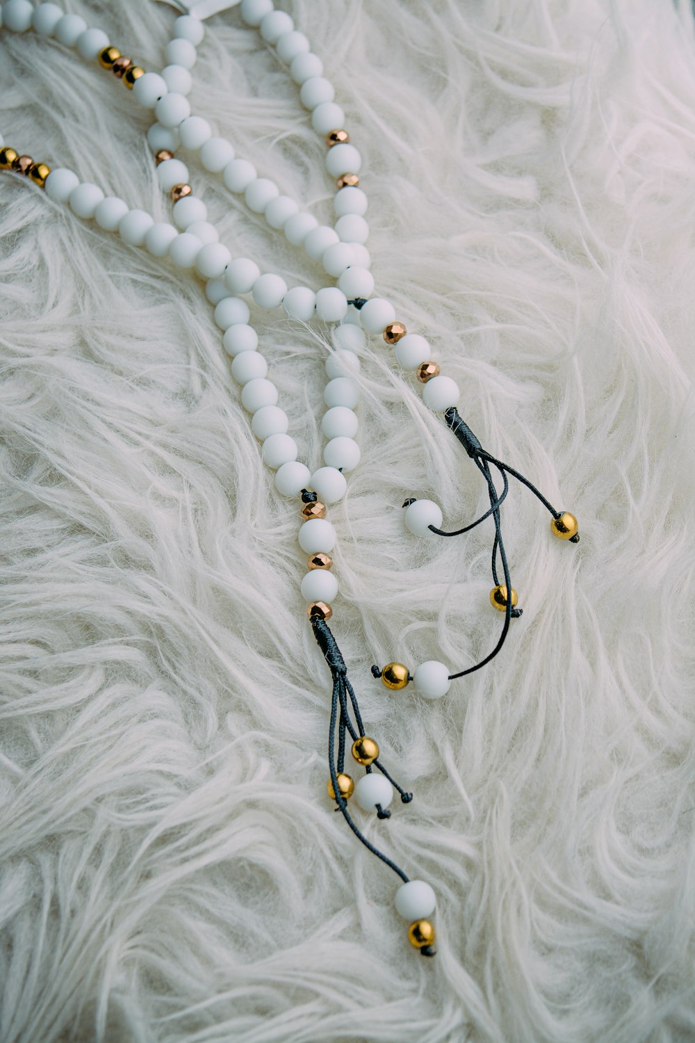 Collier de perles noir et marron sur textile blanc