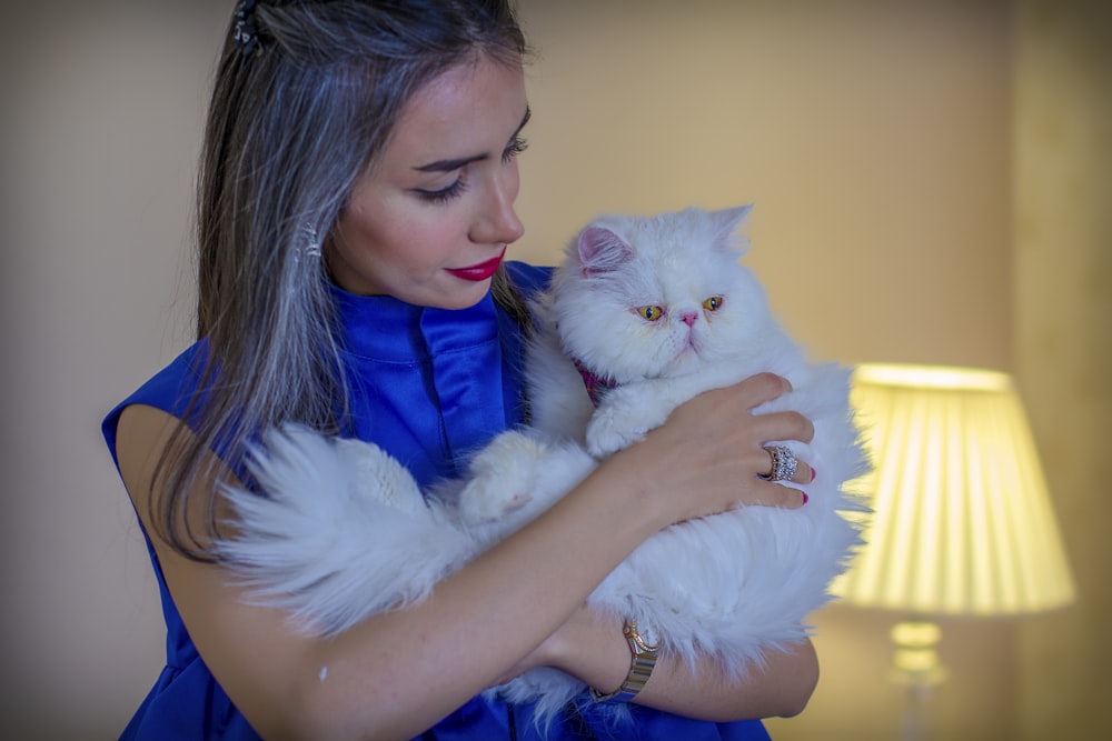 woman in blue shirt holding white cat