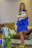 A sleek cat modeling a vibrant, custom-made dress in a bright, cheerful room.