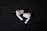 A pair of white, wireless earbuds lie on a dark surface. The earbuds have a sleek and modern design, with visible black accents and silicone ear tips. Their curves and glossy finish stand out against the matte background.