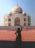 Smiling traveler standing in front of the Taj Mahal at sunset, capturing a joyful moment.