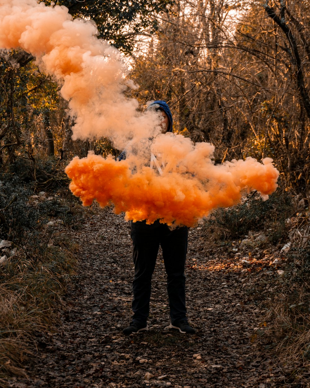 person in black pants and black boots standing on orange smoke
