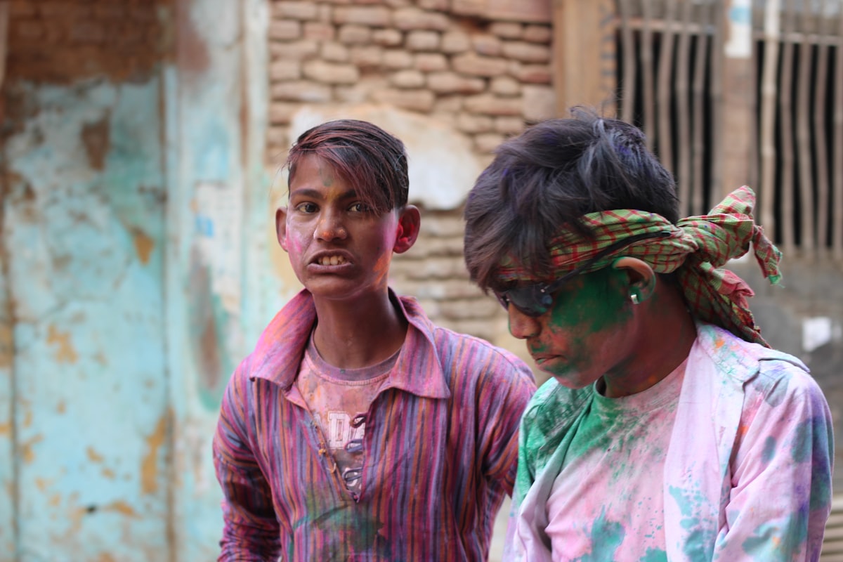 Two men covered in pink and white Holi powder. Photo by Ravi Sharma on Unsplash.