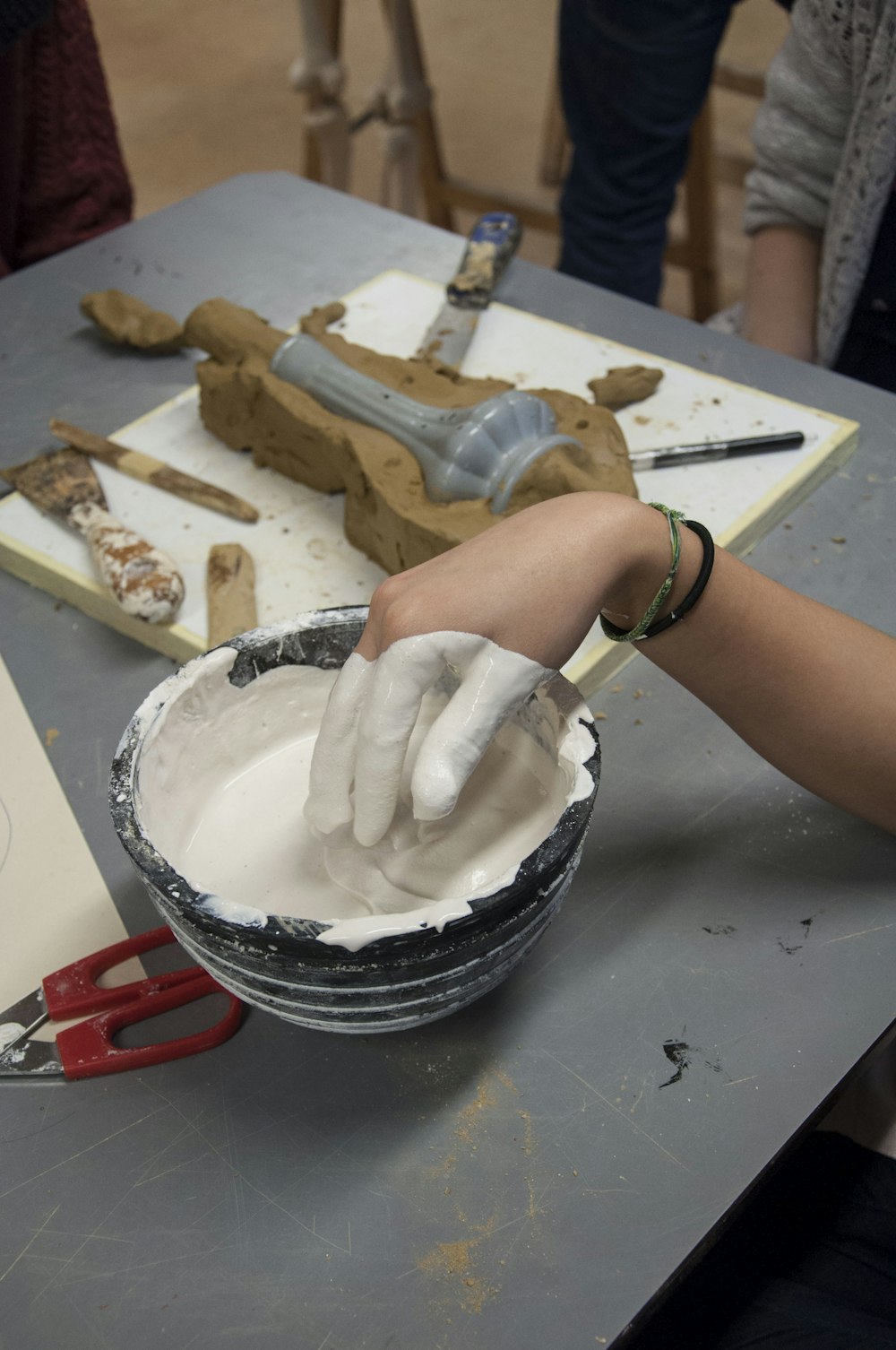 person holding white cream on black and white ceramic bowl