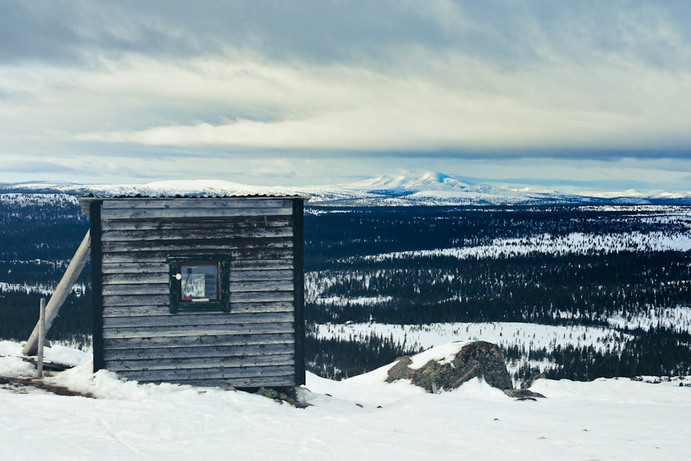 graues Holzhaus auf schneebedecktem Boden