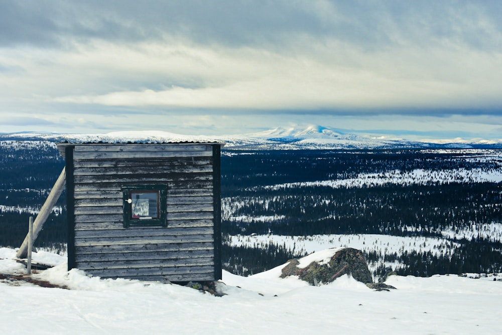 gray wooden house on snow covered ground