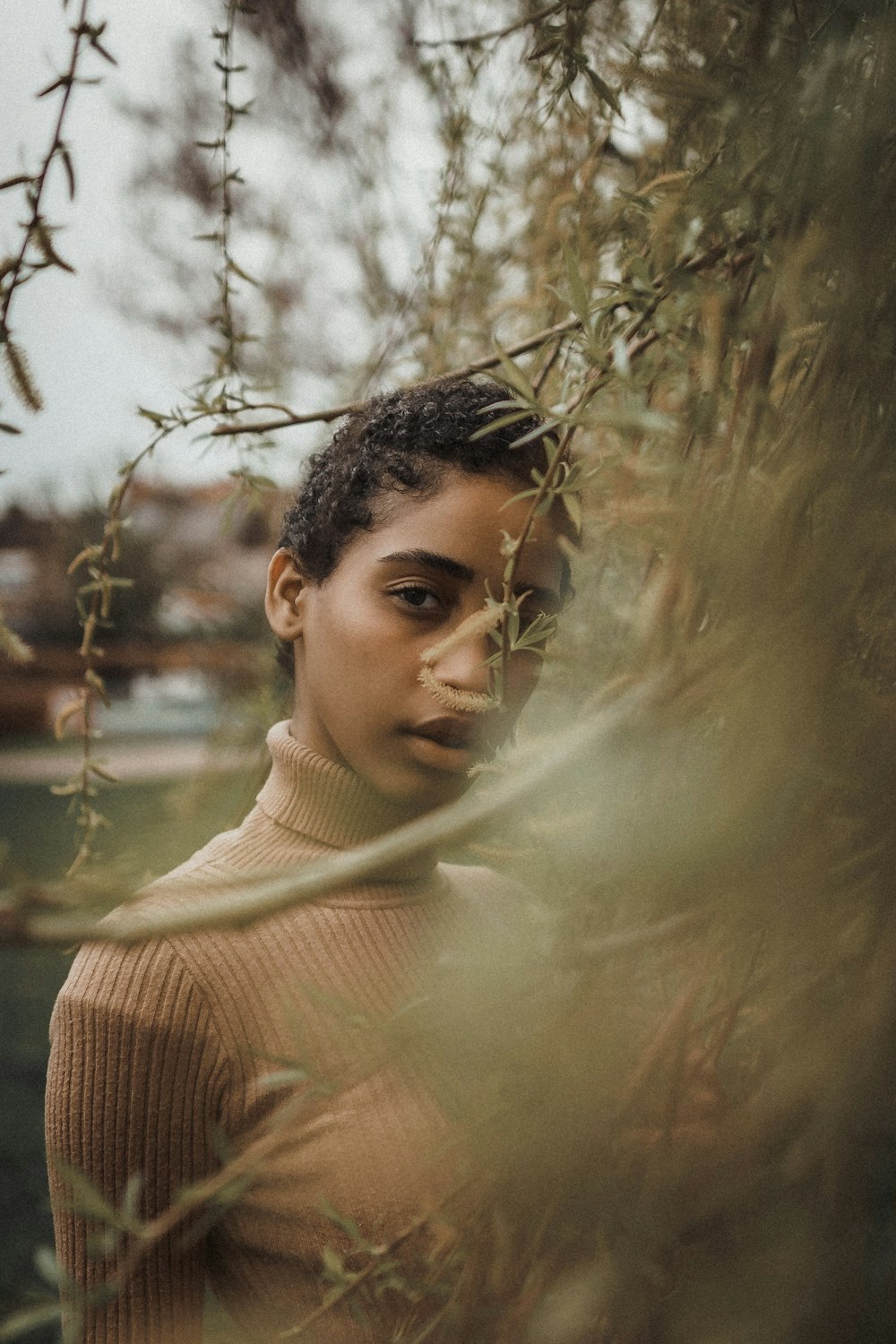 man in brown knit sweater standing near body of water during daytime