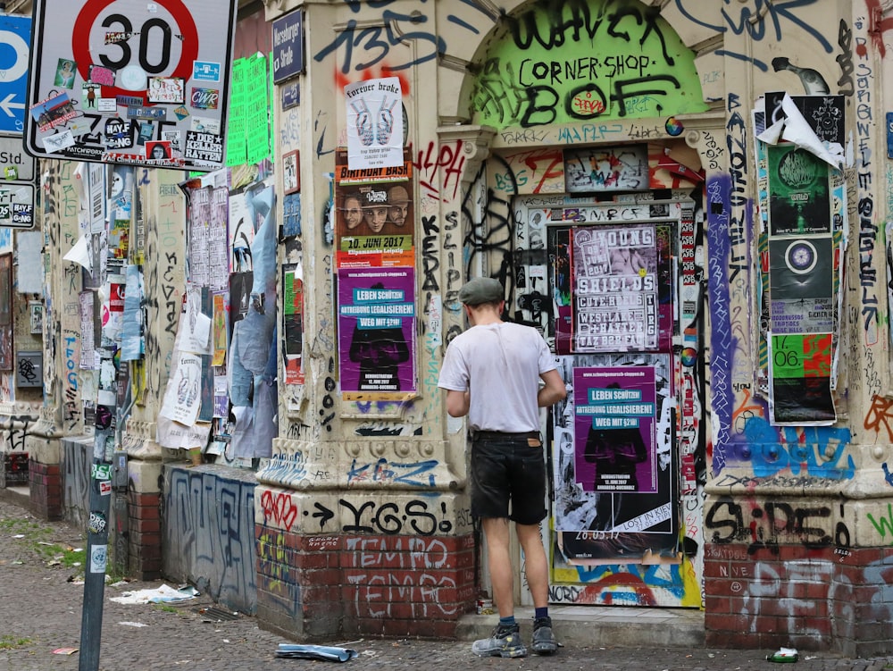 man in white t-shirt and black shorts standing in front of store