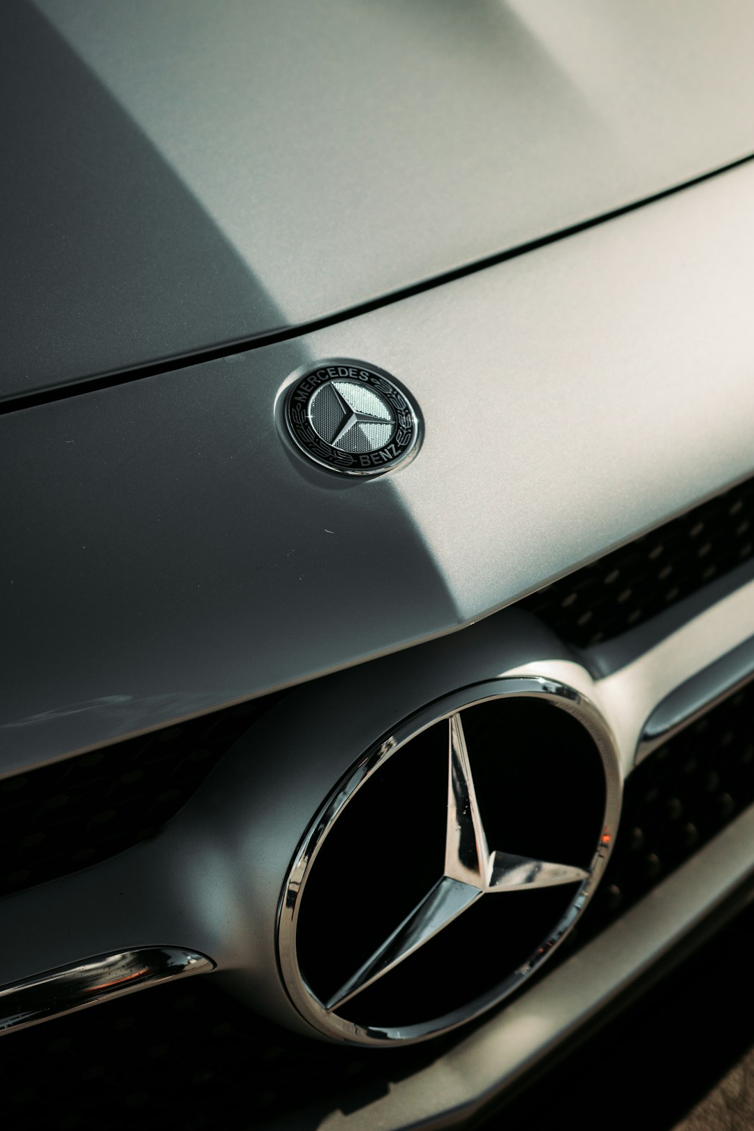 silver mercedes benz emblem on gray car