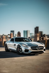 A shiny sports car parked outdoors reflecting the city skyline at dusk.