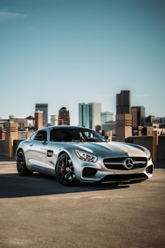 A shiny sports car parked outdoors reflecting the city skyline at dusk.