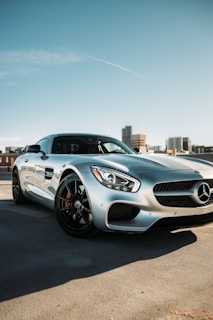 A shiny silver sedan reflecting the Dubai skyline under a clear blue sky.