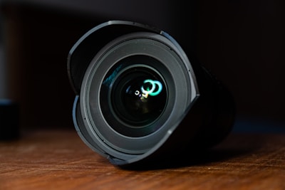 A close-up of a camera lens on a wooden table.