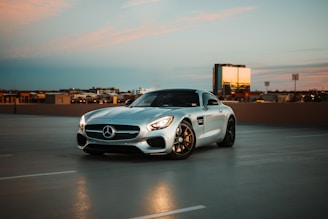 A sleek luxury car parked in front of a modern Dubai skyline at sunset.