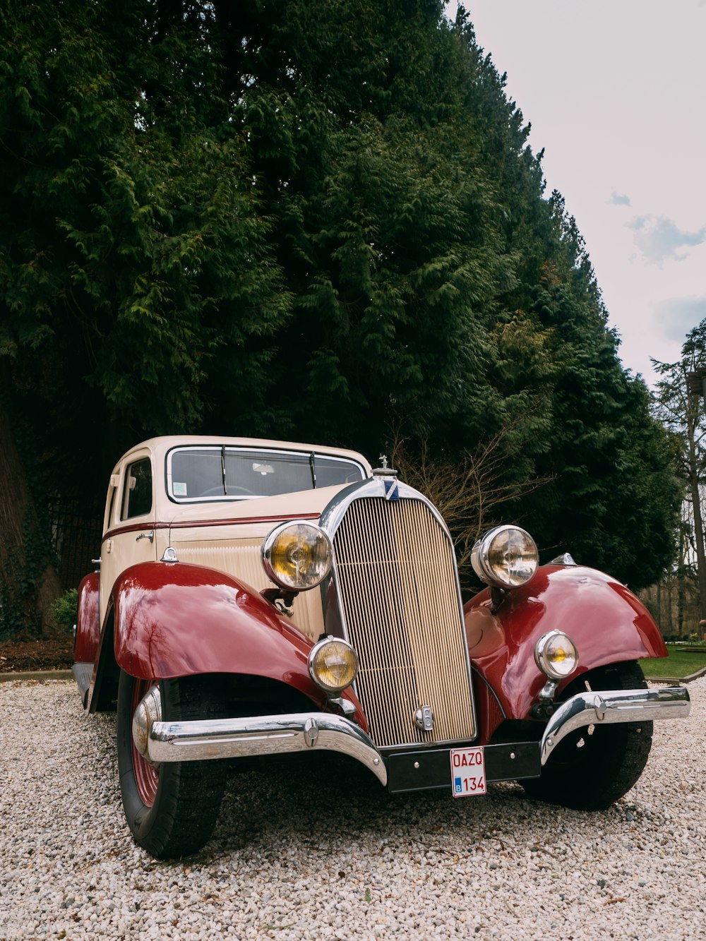 red and white vintage car on gray asphalt road during daytime