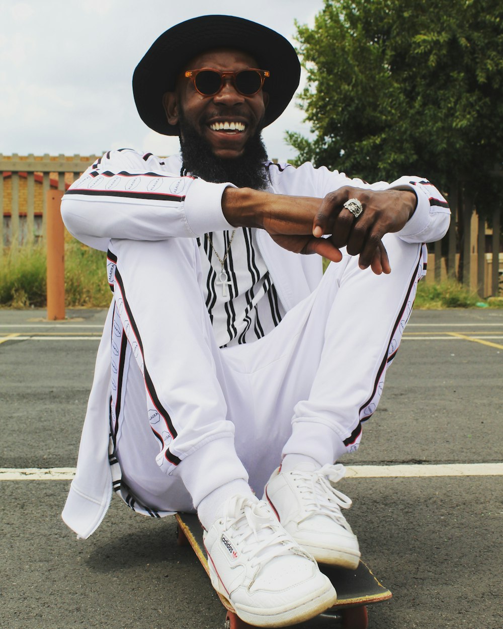 man in white hoodie and pants sitting on road during daytime