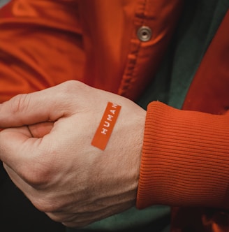 orange and white textile on persons hand
