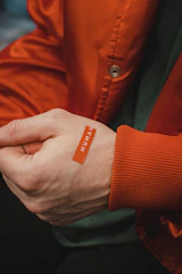 Soft silicone label stitched onto the sleeve of a dark brown sports jacket.
