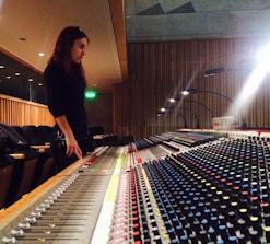 Sound engineer adjusting mixing console in a cozy studio filled with instruments.