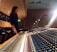 A focused audio engineer adjusting knobs on a high-end mixing console in a cozy studio.