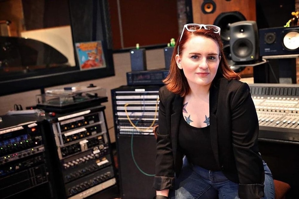 woman in black blazer standing near audio mixer