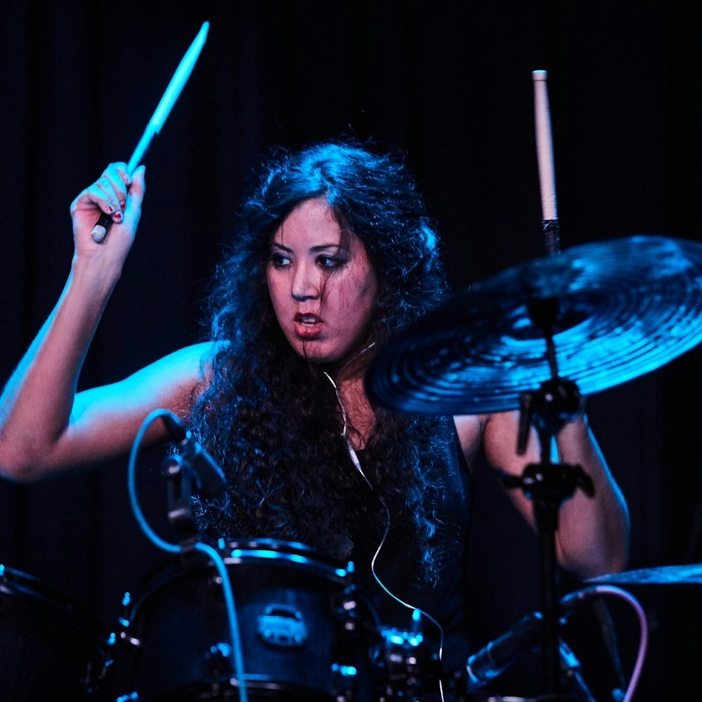woman in black sleeveless top playing drum